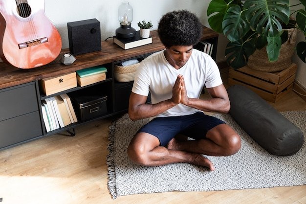 African american man meditating with hands in prayer in living room Meditation Spirituality