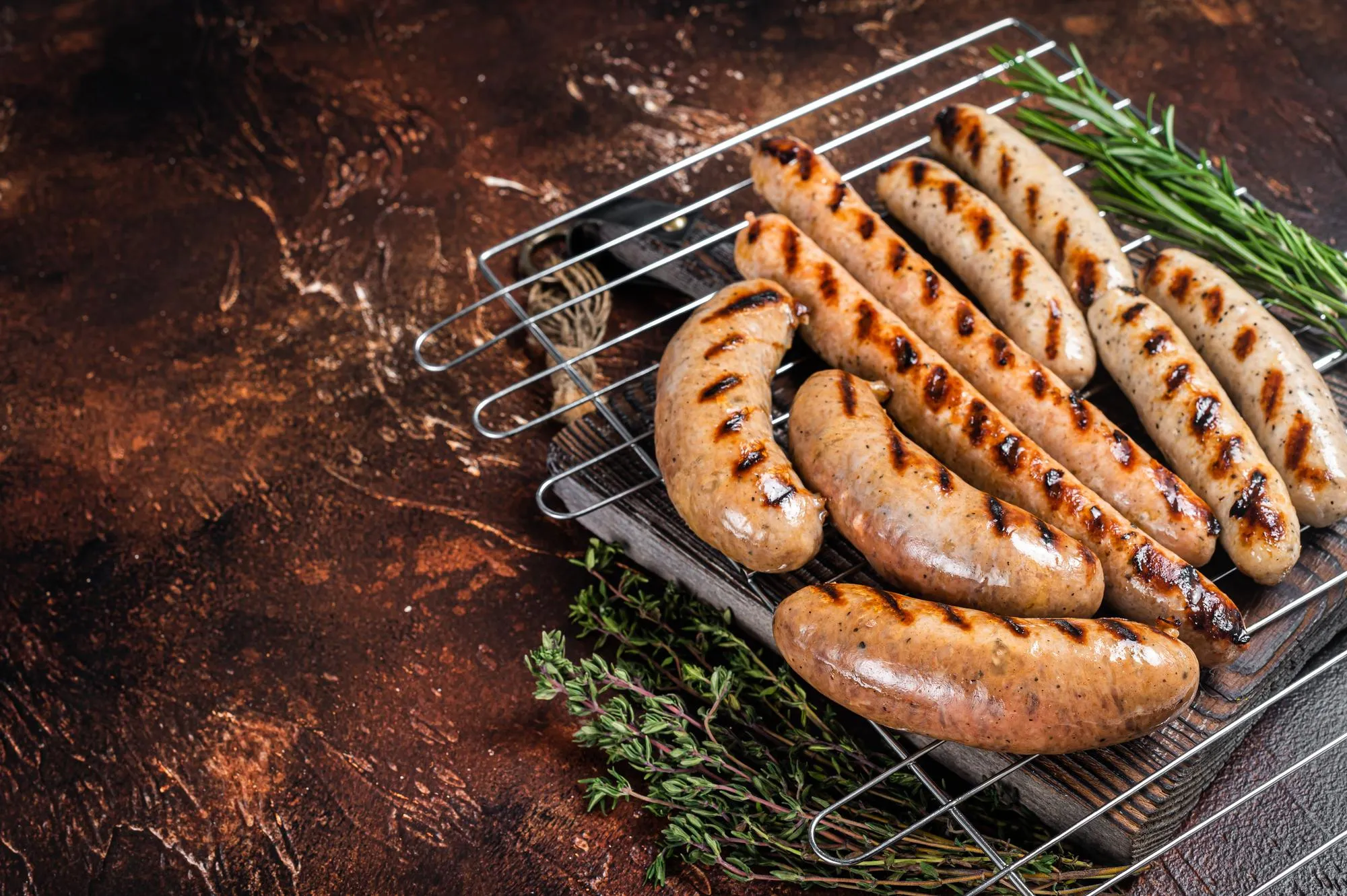 Assortment of different bbq grilled sausages with Beef pork lamb and chicken meat on a grill Dark background Top view Copy space