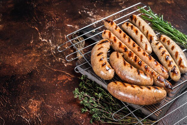 Assortment of different bbq grilled sausages with Beef pork lamb and chicken meat on a grill Dark background Top view Copy space