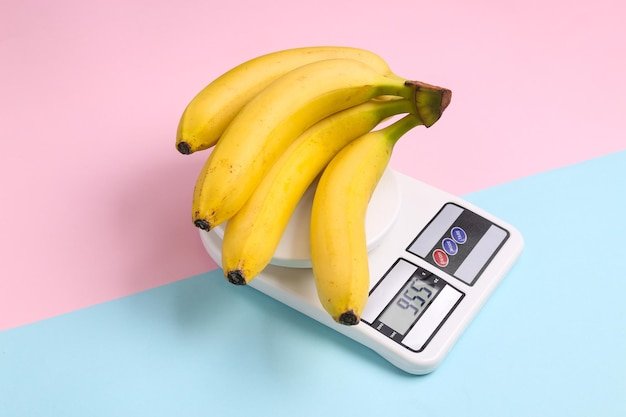 Bananas on a kitchen scale bluepink pastel background