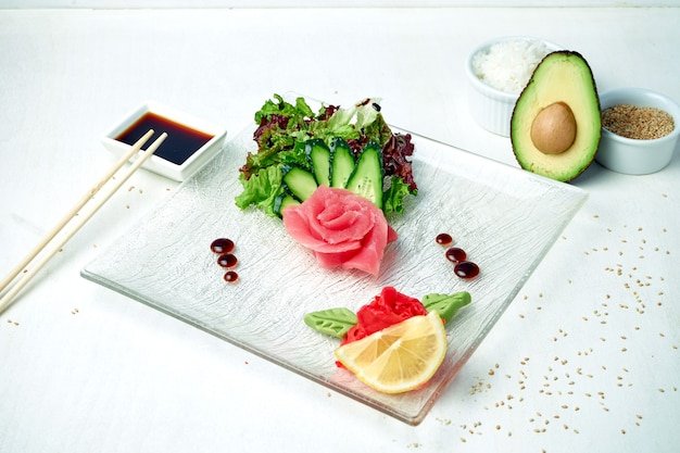 Classic Japanese sashimi - tuna with salad on a white plate in a composition with ingredients