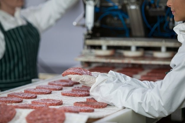 Female butcher processing hamburger patty