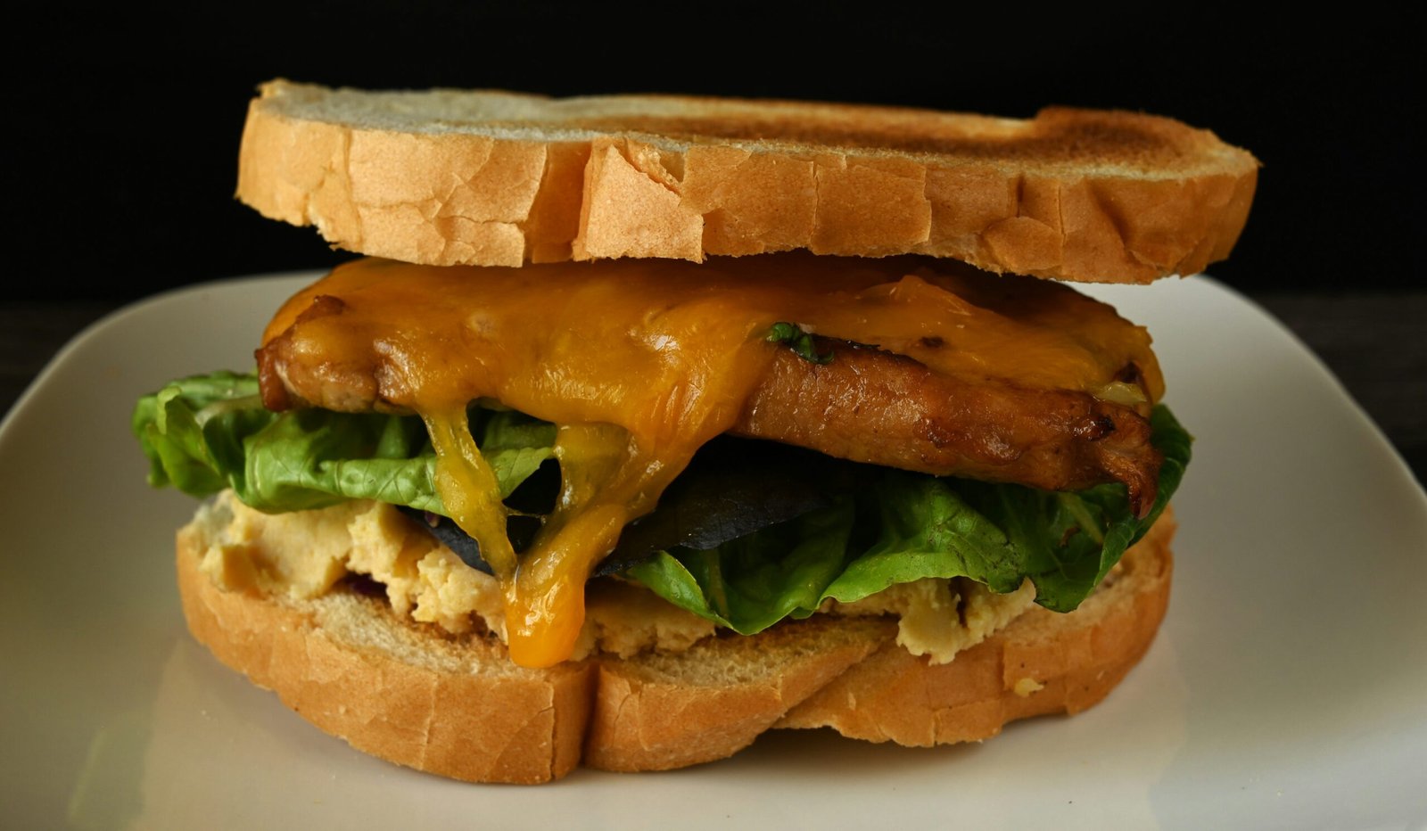 A sandwich on a plate with cheese and lettuce