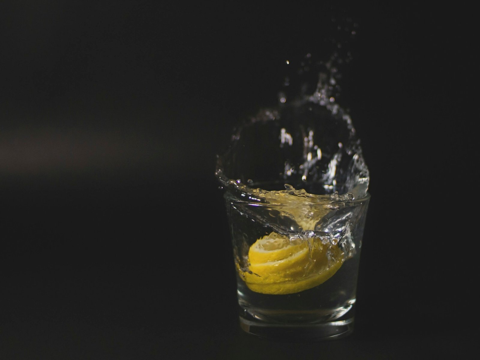 clear drinking glass with ice and yellow liquid