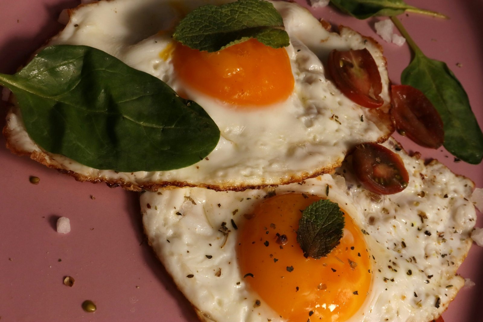 Two fried eggs with garnishes look delicious.