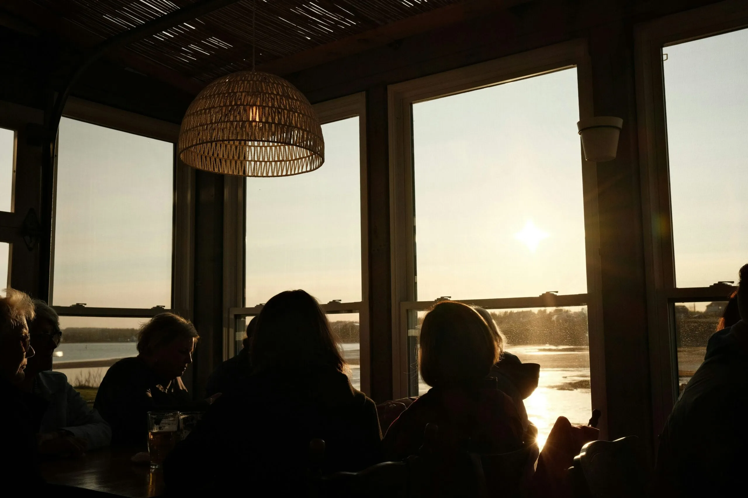 Silhouettes of people watching sunset over water