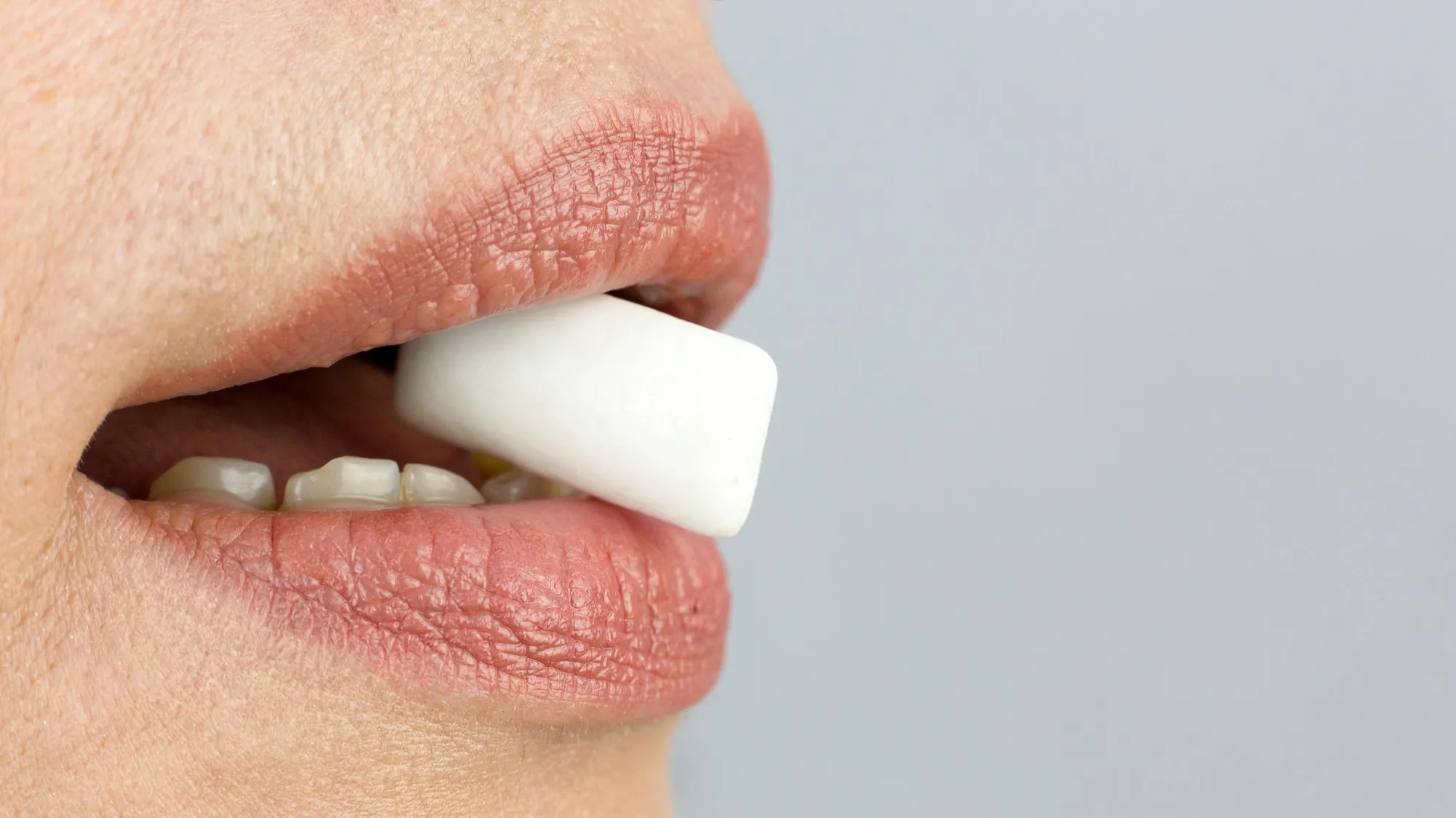 Pad of chewing gum between teeth, close-up.
