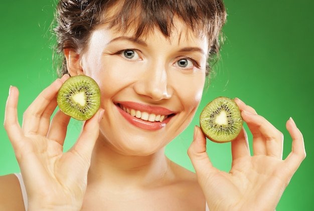 Young smiling woman holding kiwi
