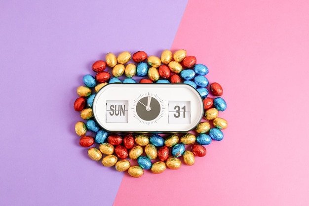 Alarm clock with easter time and date and easter eggs on lilac pink