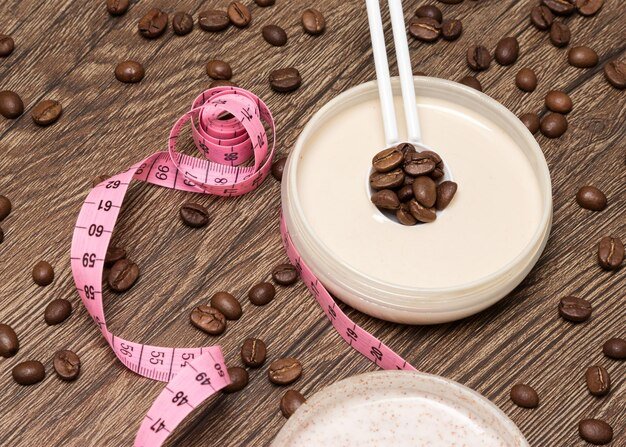 Anticellulite cosmetics with caffeine Cellulite cream with coffee essential oil on wooden surface