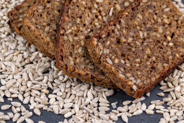 Black rye bread cut into chunks with sunflower seeds, a loaf of bread with sunflower seeds added to the dough