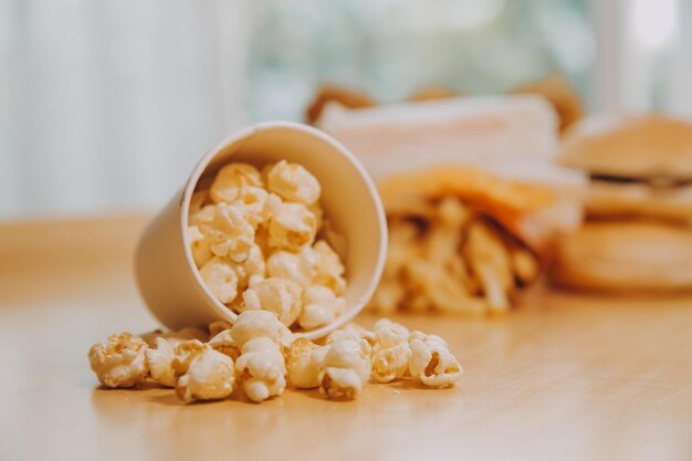 A bucket of popcorn topview warm colors light brown wooden background flat lay daylight macro closeup