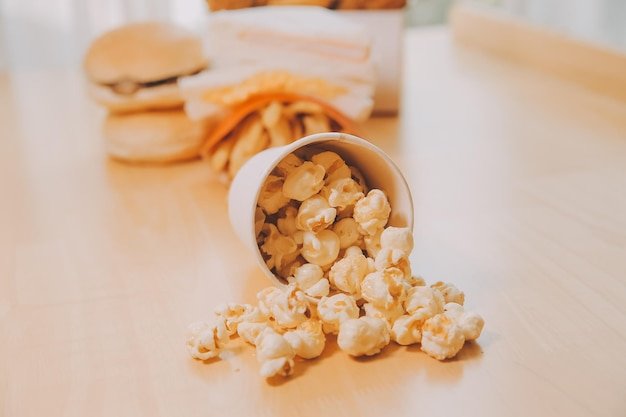 A bucket of popcorn topview warm colors light brown wooden background flat lay daylight macro closeup