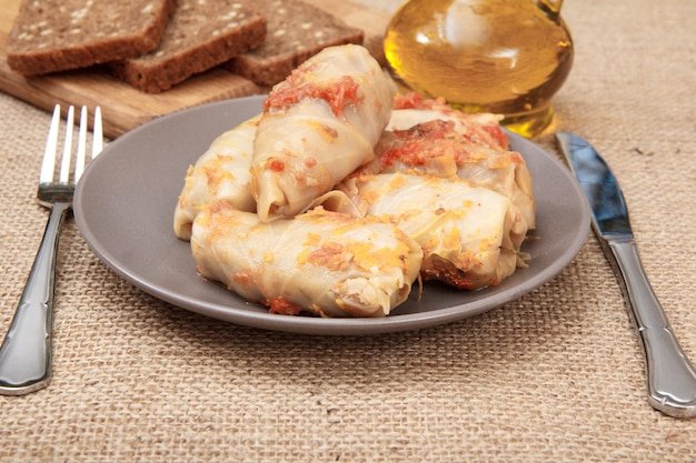 Cabbage rolls stuffed with rice and meat a fork a knife a bottle with sunflower oil and bread