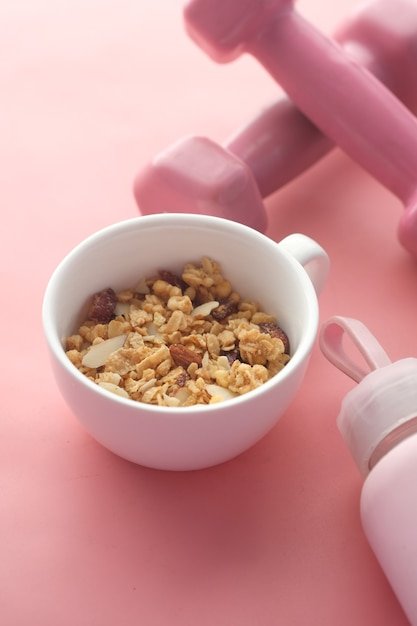 cereal breakfast and dumbbell in bowl on pink background