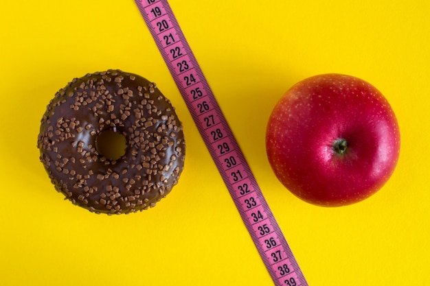 Chocolate donut,red apple and pink centimeter on yellow