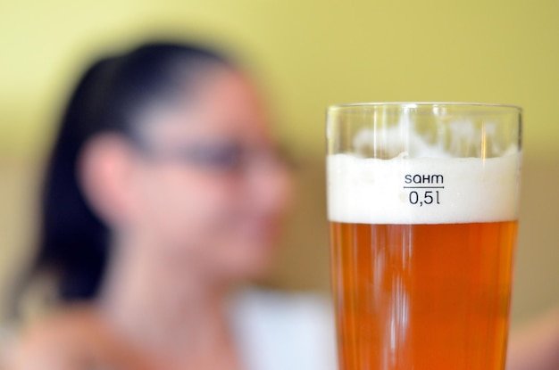 Close-up of beer glass with mature woman in background