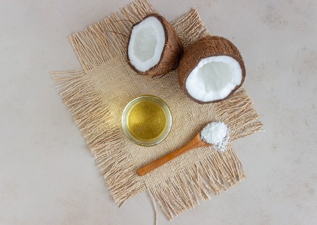 Coconut oil in a jar and fresh coconuts on a beige surface. Natural cosmetics.