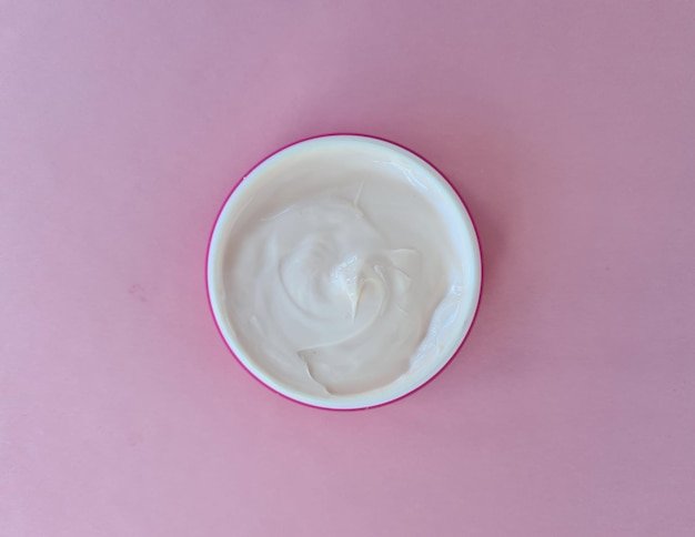 Cosmetic antiaging white cream on pink background