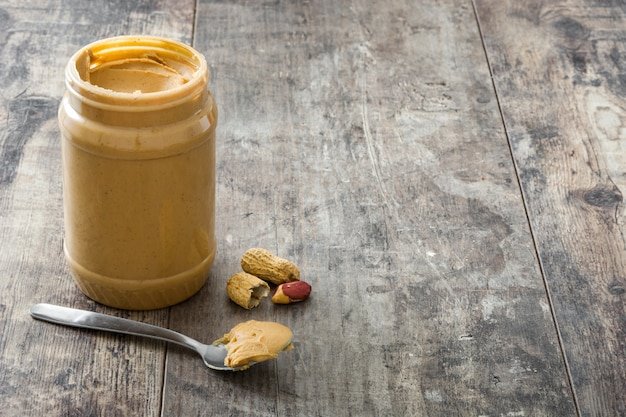 Creamy peanut butter and spoon on wooden 