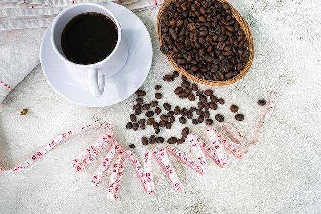 Cup of coffee and coffee beans background with measure tap on white desk Beverage and diet concept Directly above Flat lay Copy space