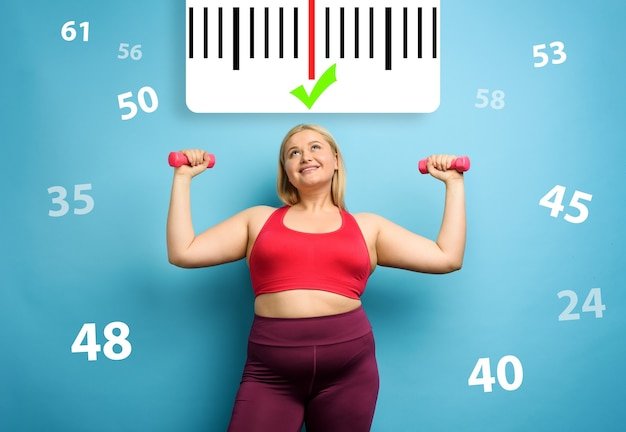 Fat girl does gym at home with satisfied expression because she decrease her weight. Cyan background