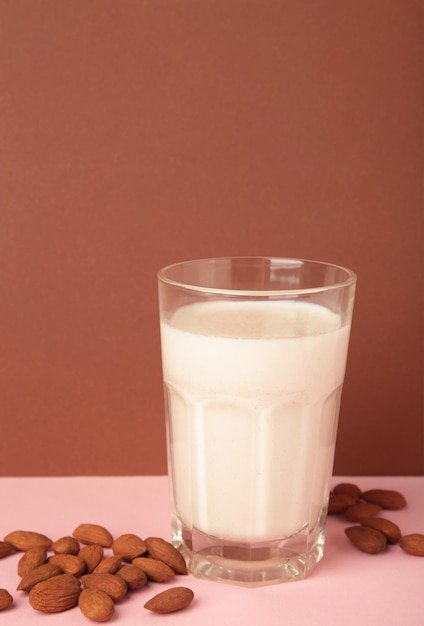 Fresh almond milk in glass and almonds on brown background Healthy vegan plant based alternative milk replacer Space for text