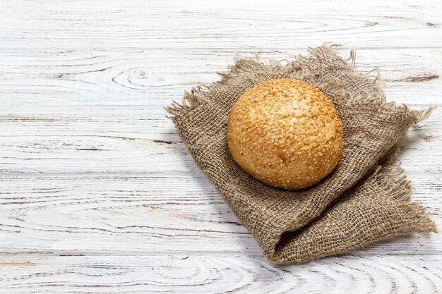 Fresh baked bread or bun with sesame and sunflower seeds on wooden table