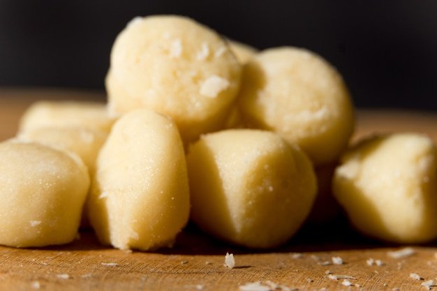 Gnocchi pasta precooked on a wooden board with grated cheese Macro close up Selective focus