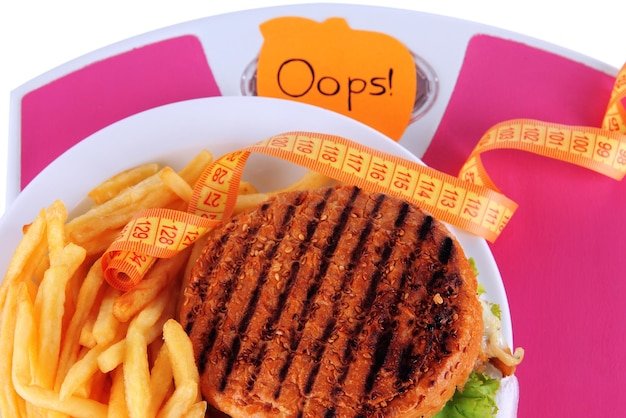Hamburger french fries on plate on scale closeup