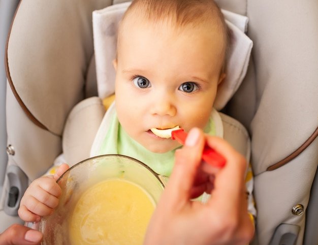 Hand carefully feeds a cute healthy newborn girl with baby food