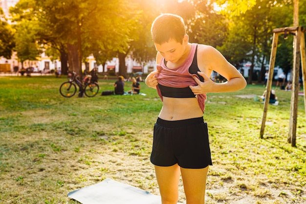 happy teenage girl with short hairstyle, in sportswear, demonstrates press with cubes in public park