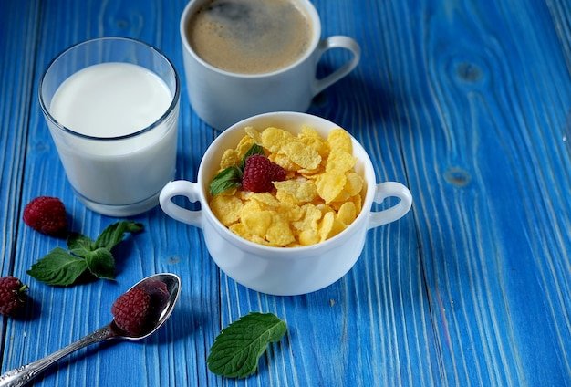 Healthy eating food and diet concept Cornflakes with berries milk and coffee for breakfast Blue wooden background