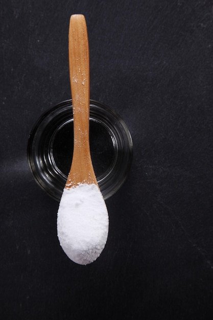 High angle view of powdered sugar in spoon over black background