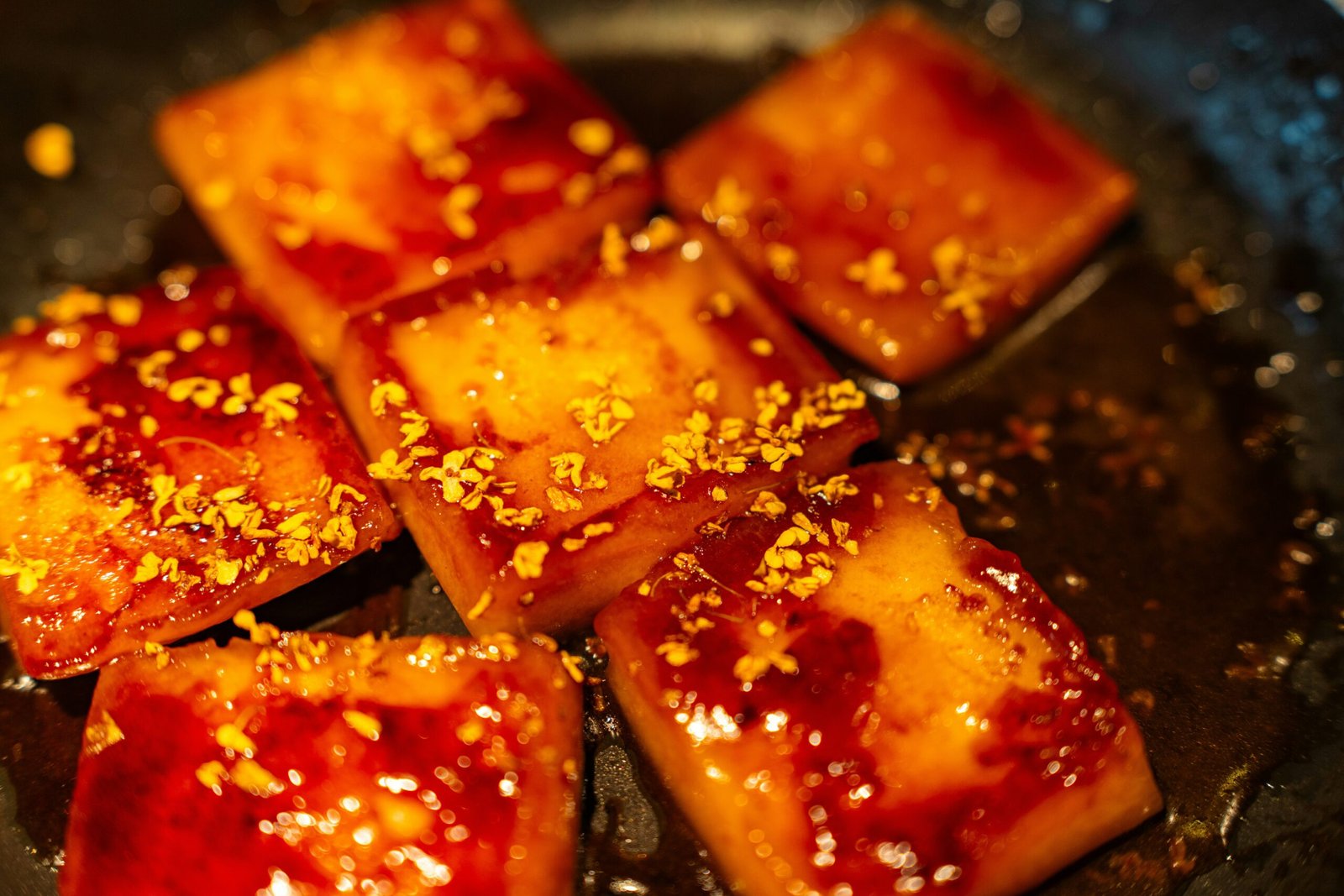 Square pieces of glazed food sprinkled with orange zest.