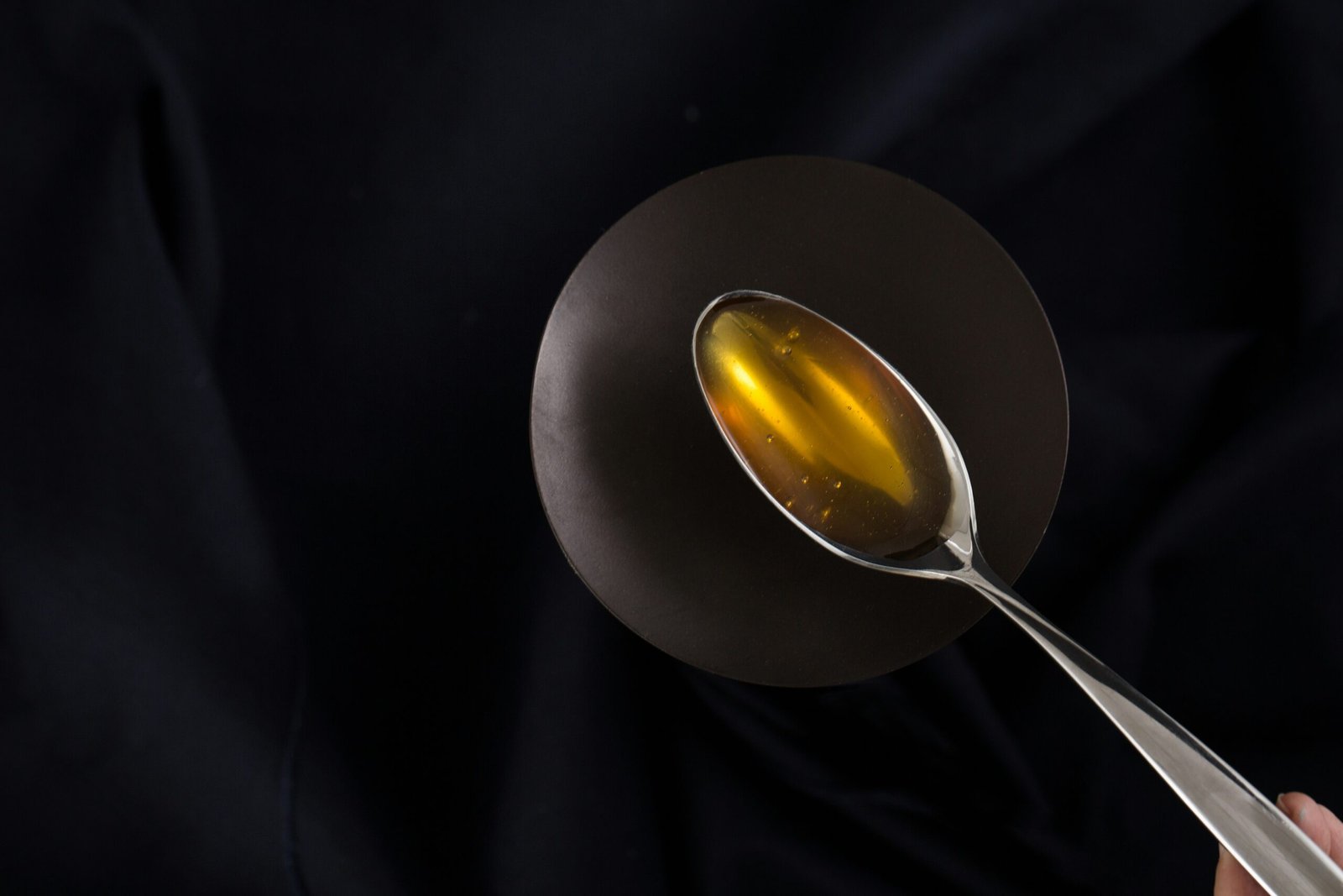 a person holding a spoon with a liquid inside of it