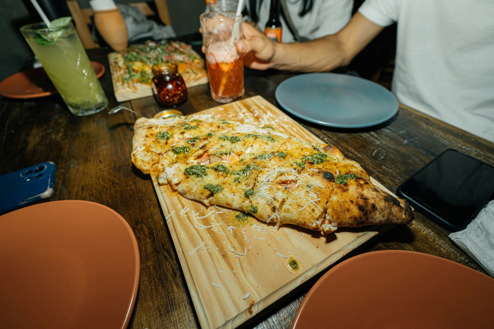 a person sitting at a table with pizza and drinks