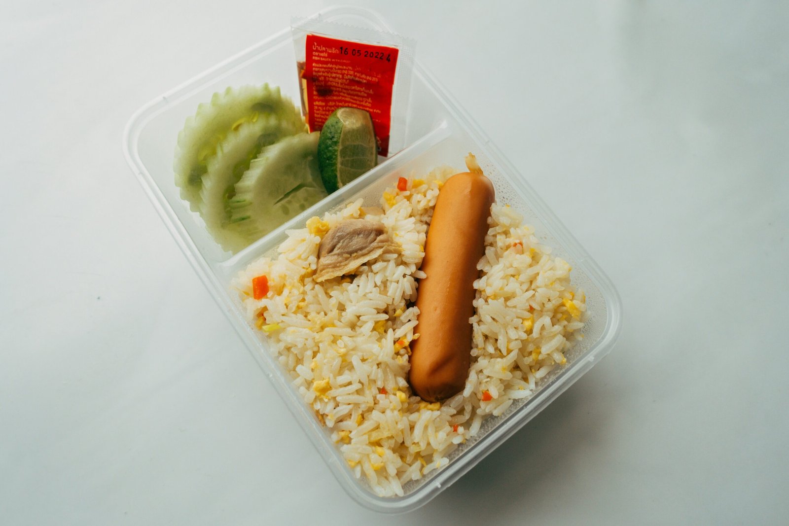 a plastic container filled with rice and a hot dog