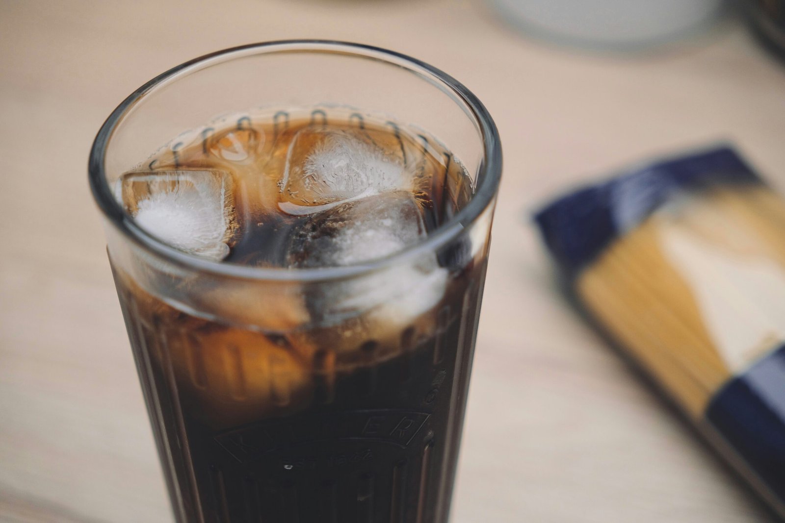 a glass of soda sitting on top of a wooden table