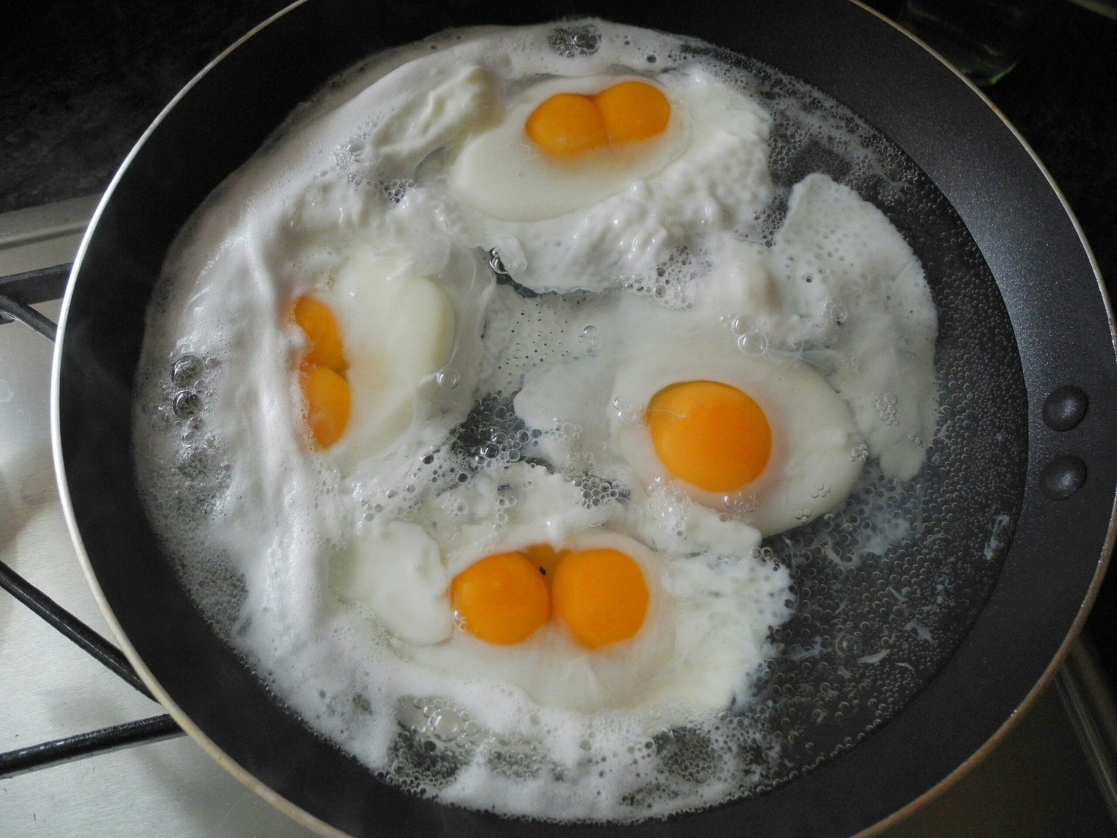 three eggs frying in a frying pan on a stove
