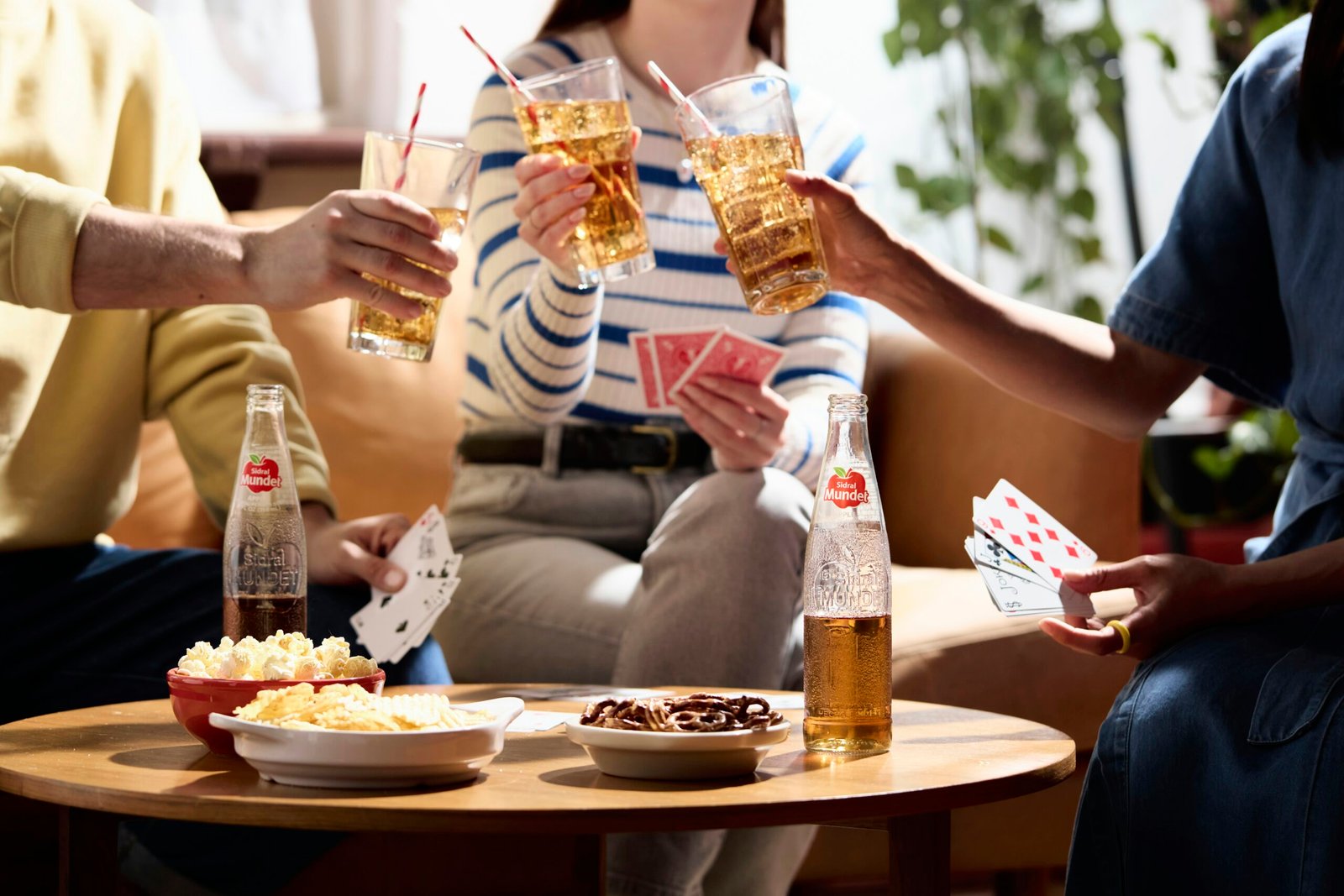 Friends are playing cards and enjoying drinks together.