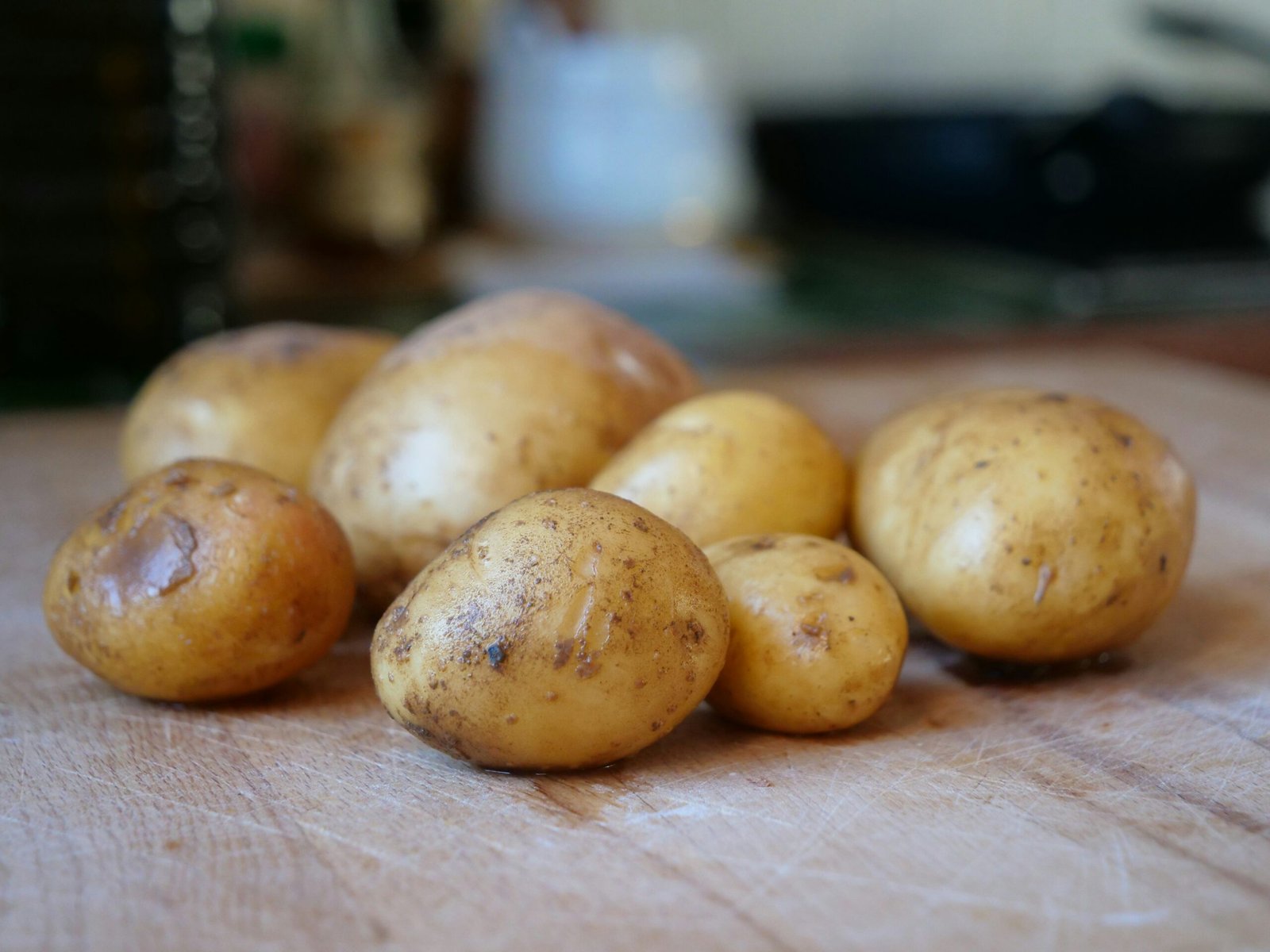 Several raw potatoes resting on a wooden surface