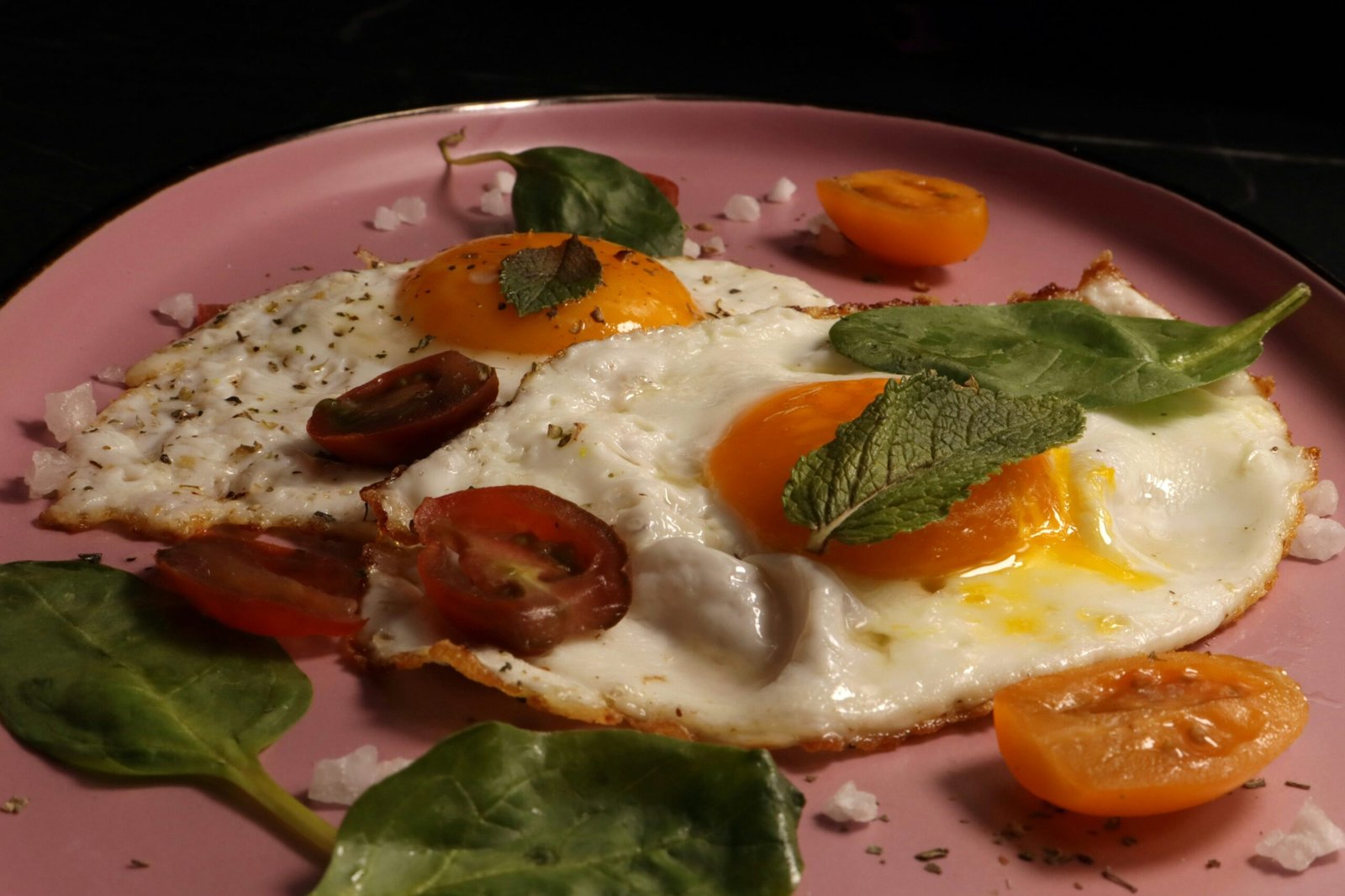 Fried eggs are served with tomatoes and herbs.