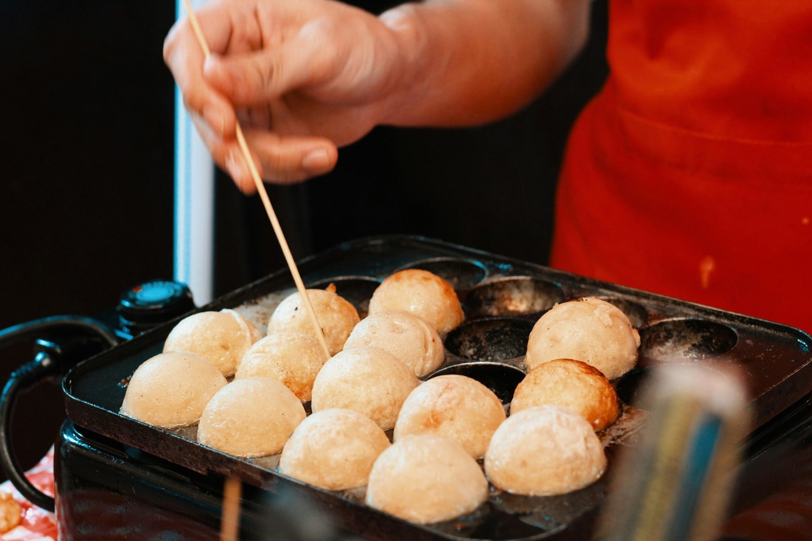 a person holding a stick over a tray of food