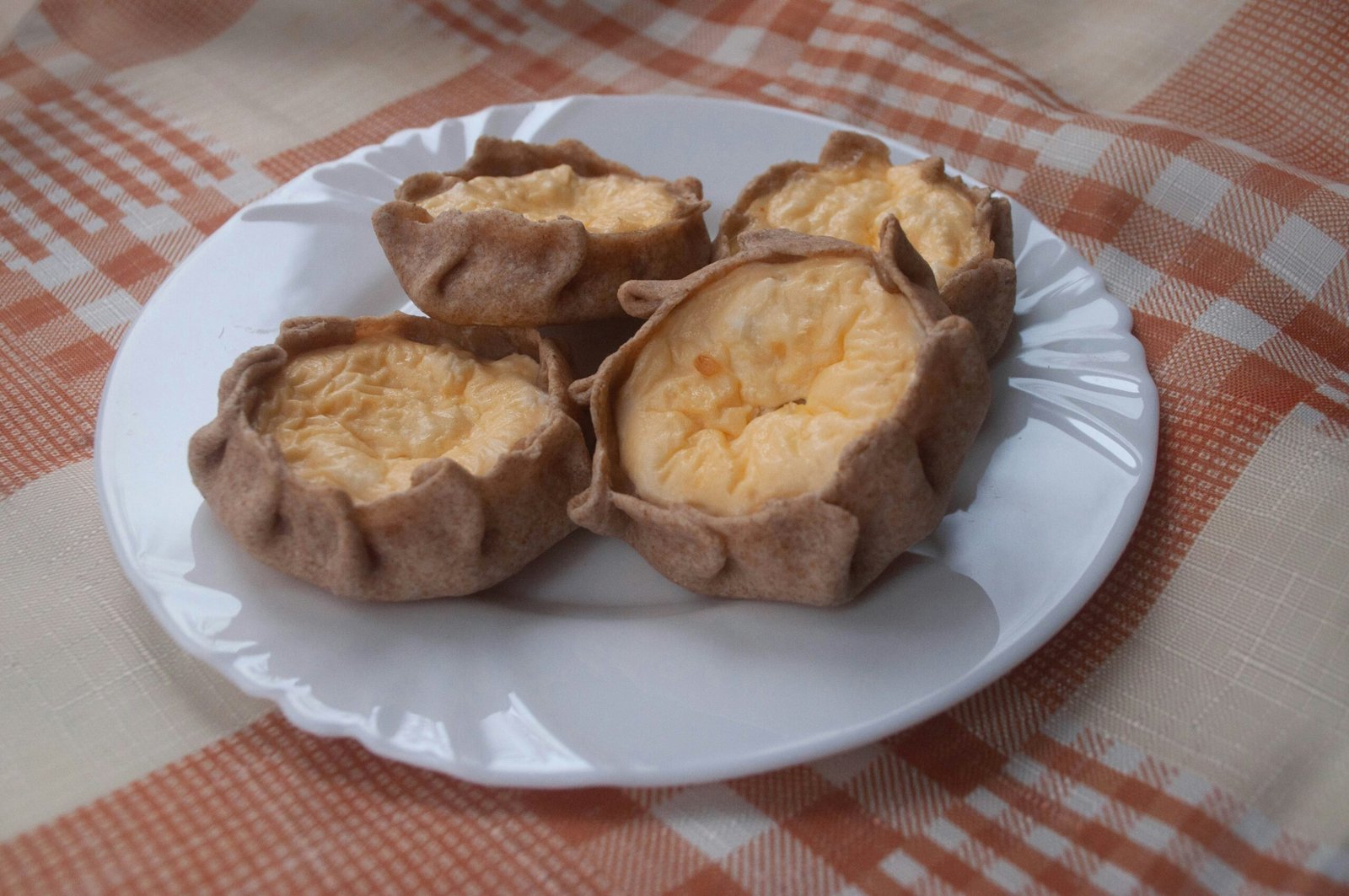 Four savory pastries sit on a white plate.