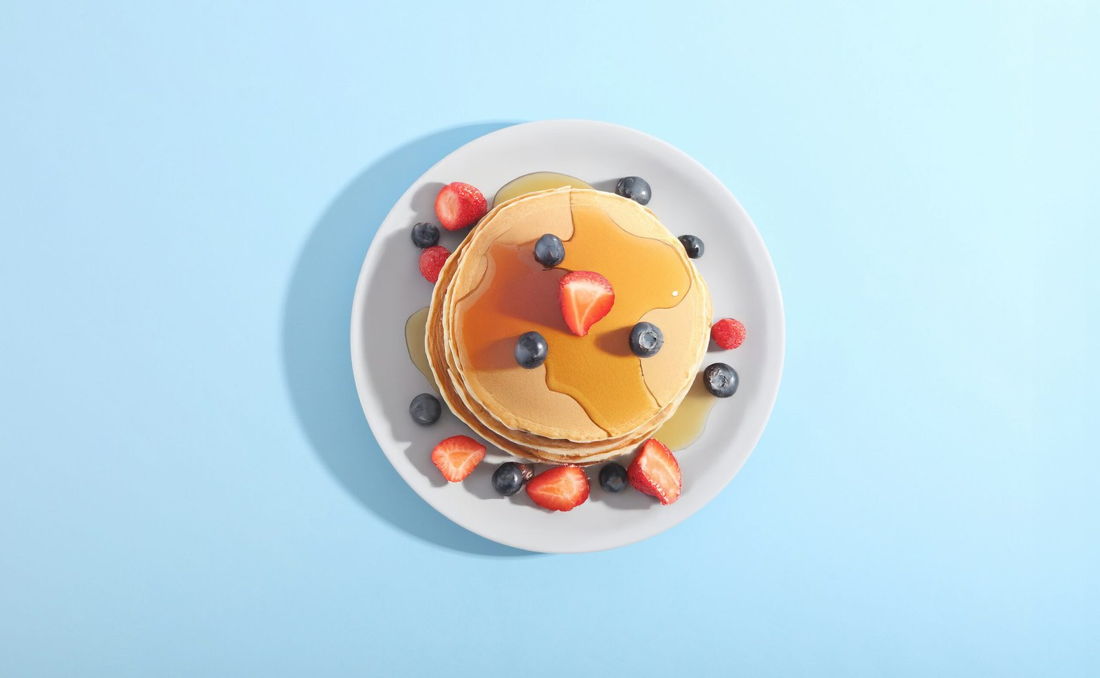 Pancakes with berries and syrup on a plate.