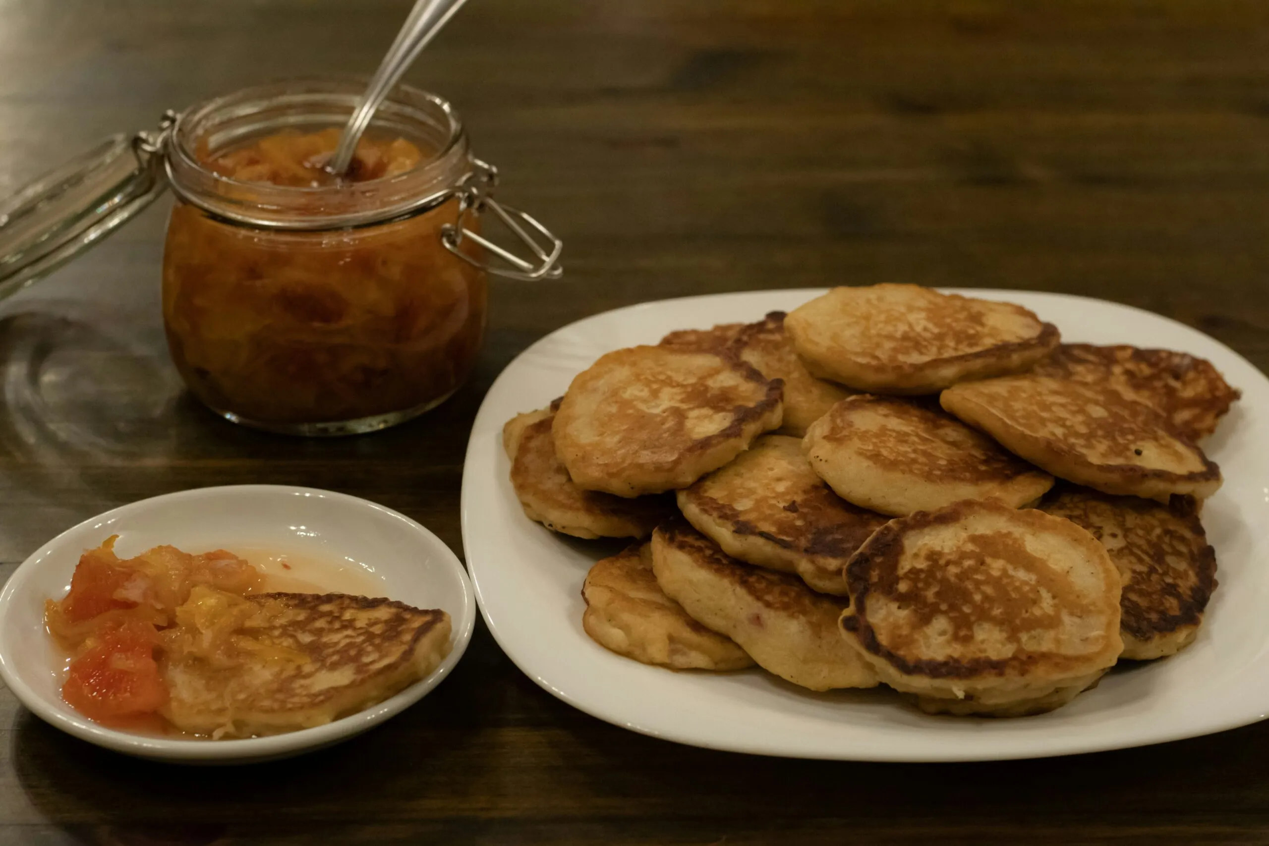a white plate topped with pancakes next to a bowl of fruit