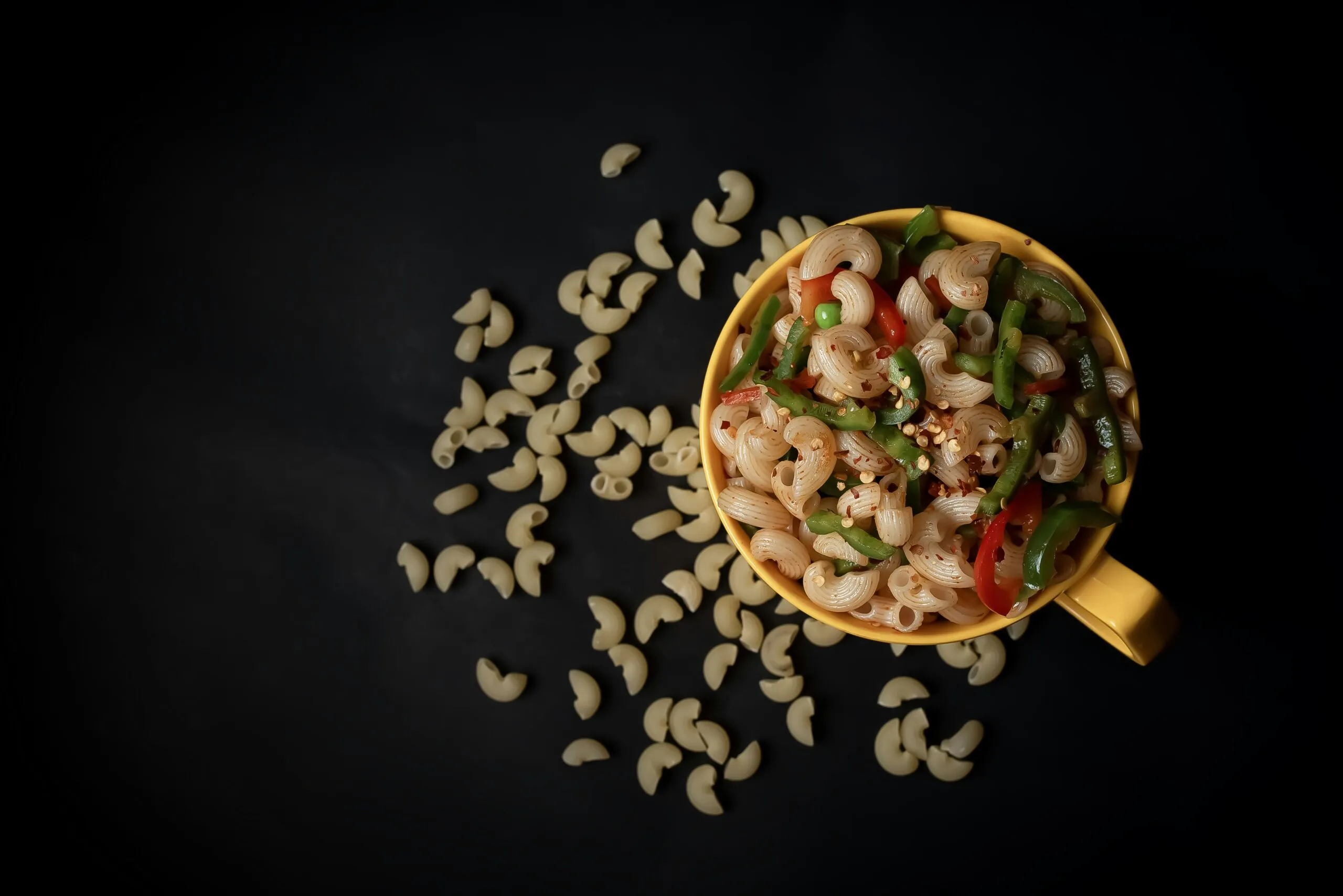 a yellow bowl filled with pasta and vegetables