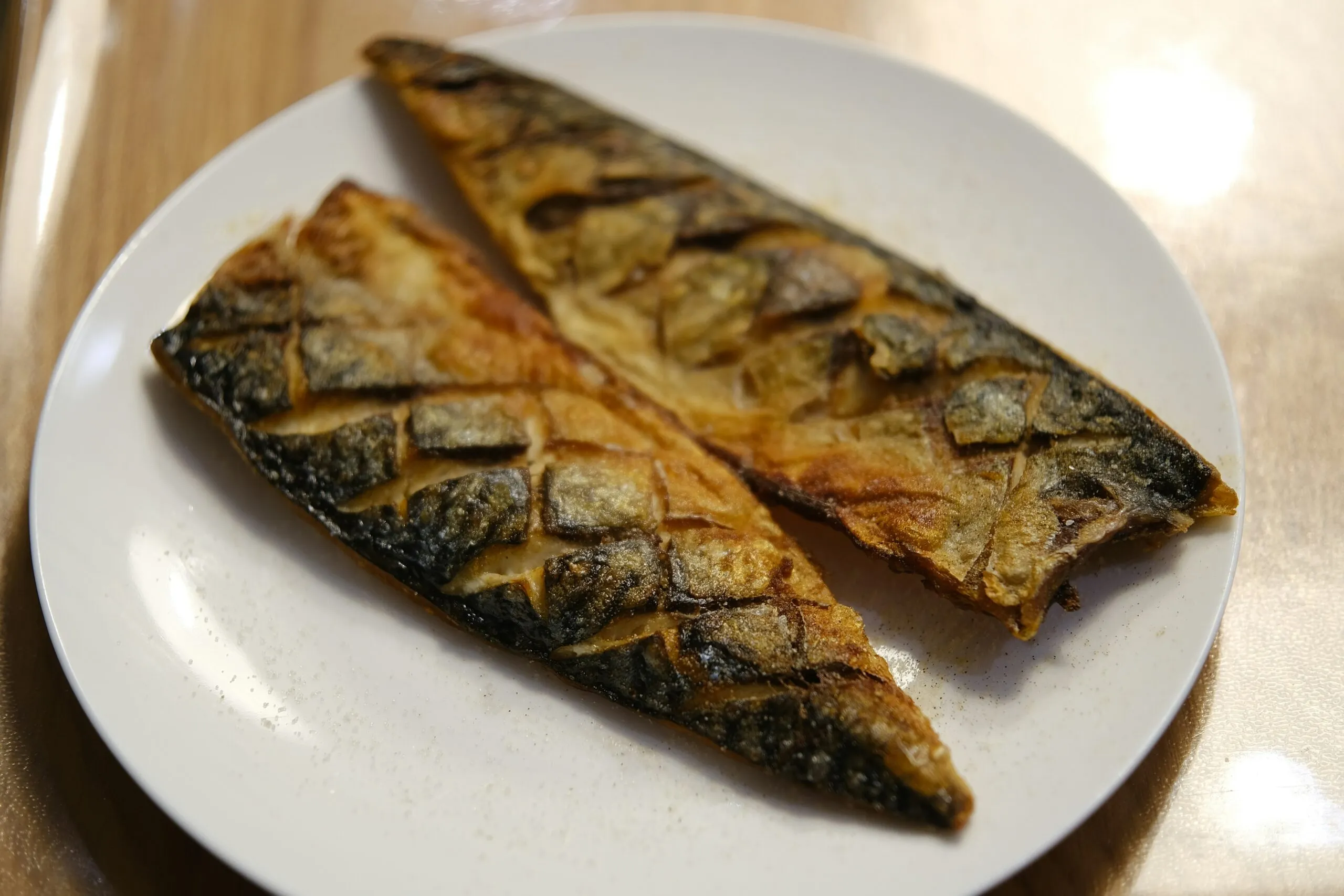 Two fried fish on a white plate on a table