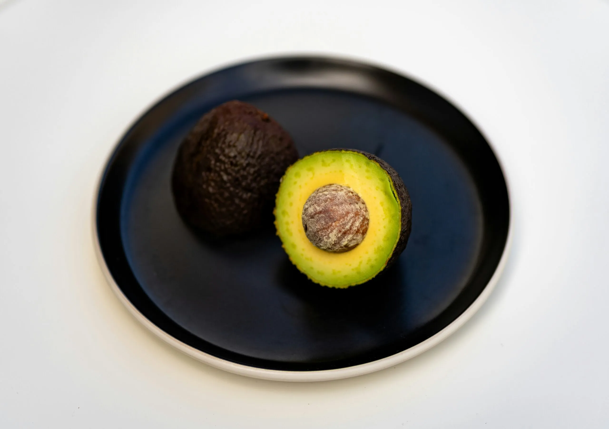 an avocado on a black plate on a white table